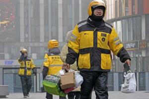 　北京市内の繁華街で働く出前アプリ「美団」の配達員＝２０２５年１２月（共同）