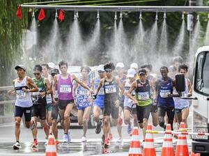 北海道マラソンで、ミストシャワーをくぐるランナー=8月、札幌市