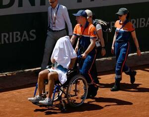 女子シングルス1回戦の第3セットで途中棄権し、車いすで運ばれる内島萌夏(手前)=パリ(共同)
