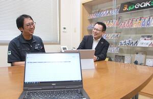 デジタル化した作業日報を見ながら意見交換する小山公一社長(左)と三条信用金庫の刈屋直利本店長=三条市