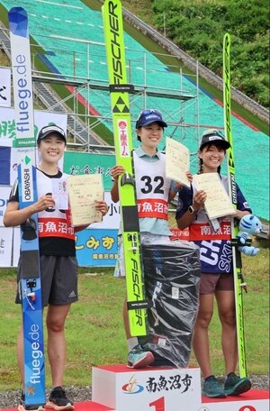 女子で優勝し、笑顔を見せる伊藤有希選手(中央)=25日、南魚沼市の石打丸山シャンツェ