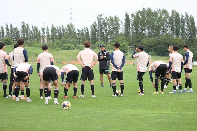 入江徹新監督の元に集まる新潟の選手たち=6月24日、聖籠町