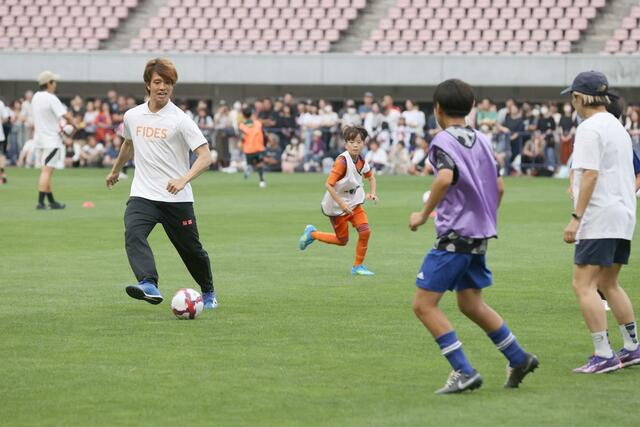 子どもたちとゲームで交流する長崎の長谷川元希＝６月１４日、デンカビッグスワン