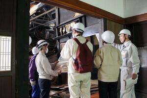 土砂崩れで被災した国指定五十嵐家住宅を視察する修理検討委員会メンバーら=阿賀町豊実
