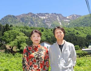 若井義貴さんと妻の香織さん。近所のお気に入りフォトスポットからは八海山が眺められる=南魚沼市山口