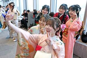 晴れ着姿で記念撮影する若者たち。地元就職への希望や国際情勢への不安など多様な関心事を語った=11日、新潟市中央区