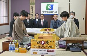 第49期棋王戦コナミグループ杯5番勝負第4局で、初手を指す伊藤匠七段。左は藤井聡太棋王=3月17日、栃木県日光市