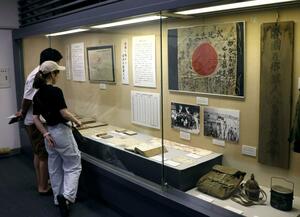 「武運長久」と書かれた日章旗や当時の生活用品、回覧文書などが並ぶ企画展=佐渡市八幡