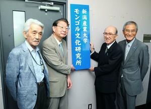 新潟産業大学の学長時代、学内に設置した「モンゴル文化研究所」の看板を掛ける北原保雄さん(中央右)=2016年、柏崎市軽井川