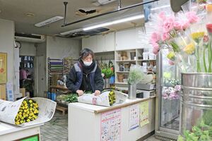 「清花園」で作業をする杵渕豊さん。店舗の天井には穴が開き、火災の爪痕が残る=魚沼市小出島