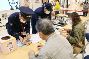 蒸しパンを配り、国際電話の利用休止を呼びかけた警察官ら=新潟市江南区