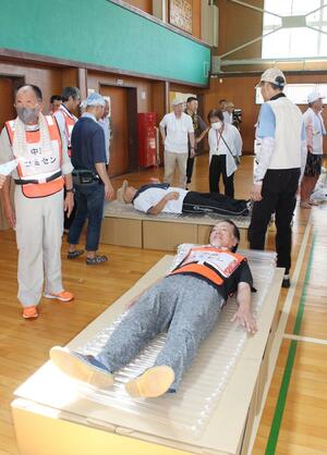 中島小学校で行った訓練で、段ボールベッドに横たわる住民=8月31日、長岡市中島3