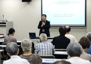 統計データなどを使い、原発の経済効果についての見解を語る藤堂史明教授=6月29日、村上市田端町