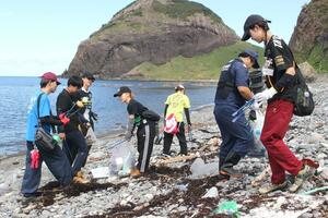 大野亀周辺の海岸に流れ着いたごみを拾う大学生=佐渡市