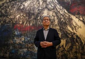 美術館に展示されている丸木位里、俊の「沖縄戦の図」を説明する佐喜真道夫。沖縄戦の体験者からの証言を基に地上戦を描いた=沖縄県宜野湾市