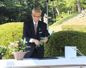 満州柏崎村の塔の前で慰霊の献花をする巻口弘さん=柏崎市緑町