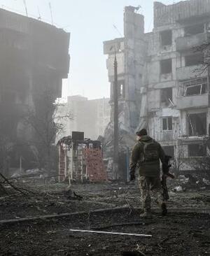 ロシア軍の攻撃を受けた住宅近くを歩くウクライナ兵=3月、ウクライナ南部ザポリージャ州オリヒウ(ロイター=共同)