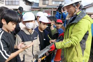 液状化した地層を採取するボーリング調査を見学する児童たち=11月5日、新潟市江南区天野3