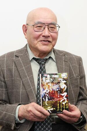 出版した小説「この子ばっかしゃ」を持つ石田哲彌さん=新潟日報長岡支社