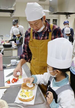 工夫を凝らしたクリスマスケーキを作る親子=柏崎市の市民プラザ