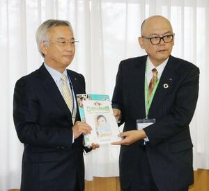 聖籠町の近藤朗教育長(左)に教材を手渡すJA北新潟の近田俊幸理事長=聖籠町役場