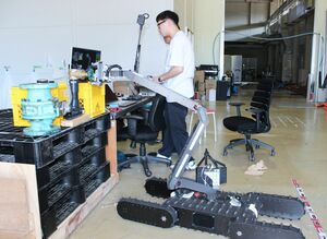 災害救助ロボットでメーターの数値の読み取りや、バルブの閉栓の作業を練習するメンバー=長岡市上富岡町