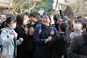 受験番号が書かれた掲示板を前に、歓喜の笑顔を見せる受験生=3月13日、新潟市中央区の新潟高