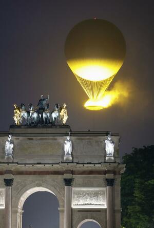 パリ五輪の開会式で点火され、浮かび上がる聖火(共同)