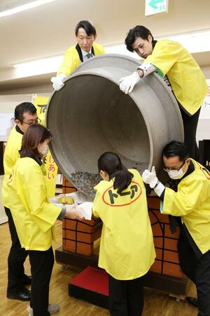 慈善釜から寄付金を取り出す従業員＝２２日、長岡市寺島町