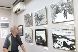 自身が撮影した村民らの写真を眺める斉藤文夫さん=新潟市西蒲区巻甲