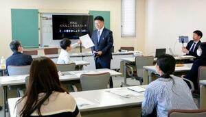 　東日本大震災にちなんだ広告企画を教材に模擬授業をする光武正夫さん（中央）＝７日午後、佐賀市