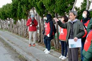 能登半島地震の津波被害の状況を説明する出村正幸さん(手前)=3月、石川県珠洲市