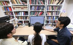「ヒューマニテクスト」を使い、ソクラテスやプラトンなどの回答を読む名古屋大の岩田直也准教授(右)と学生=名古屋市