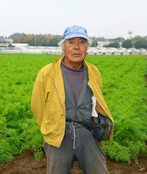 　自宅周辺に広がるニンジン畑に立つ栗原恒治さん＝１１月、千葉県富里市