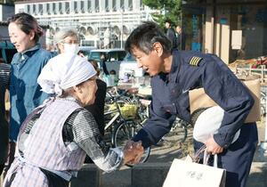 伊藤敏明さんに贈り物を渡し、感謝の気持ちを伝える粟島浦村の人たち=粟島港