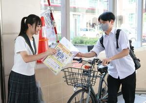 自転車駐輪場前でヘルメットの着用などを呼びかける帝京長岡高校の生徒=長岡市大手通1