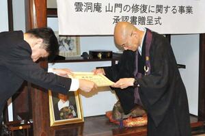 日野正夫理事長（左）から承認書を受け取る田宮隆児住職＝南魚沼市雲洞