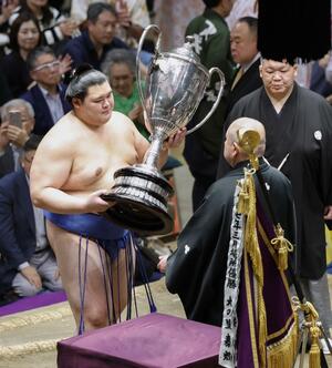 日本相撲協会の八角理事長(右)から賜杯を受け取る大の里=東京・両国国技館