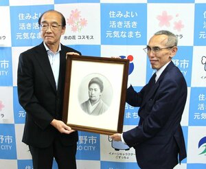 津田梅子の肖像画を持つ大津俊哉理事長(右)と加藤博幸市長=23日、阿賀野市役所