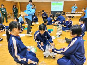 橋台に見立てた段ボールと紙を使って強い橋を作る生徒=新発田市下羽津