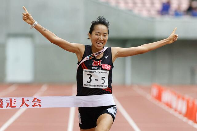 女子 女子 両手人差し指を突き上げて優勝のゴールテープを切る新潟明訓のアンカー石川桃子=新潟市中央区
