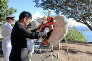 8日、米ハワイ州フォード島で開かれた日米合同追悼式典で、献花する長徳英晶・駐ホノルル総領事(手前)と、コリンズ米ハワイ方面海軍司令官(共同)