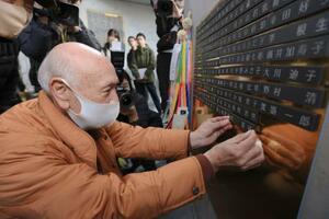 　「慰霊と復興のモニュメント」で、父喜禎さんの銘板を取り付ける昇和治さん＝１６日午後、神戸市中央区