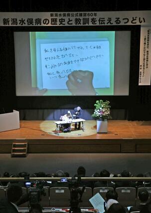 式典で後世へのメッセージとして筆談で話す胎児性水俣病患者の古山知恵子さん＝３１日、新潟市中央区