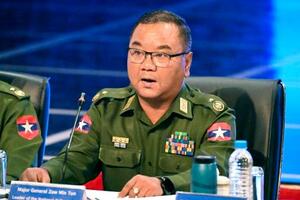 14日、ミャンマー最大都市ヤンゴンで記者会見する軍事政権のゾーミントゥン報道官(共同)