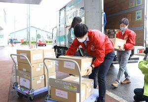 投票用紙などが入った段ボール箱を運ぶ新潟市の選管職員ら=8日、新潟市東区