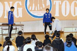 西内野小の児童とリフティングをする千葉和彦選手(左)と秋山裕紀選手(中央)=12日、新潟市西区内野上新町