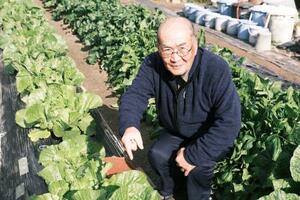 自宅の畑で育てた野菜と濱口光緒さん=2025年12月、大阪府摂津市