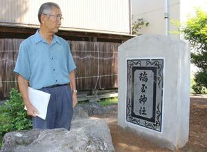 修復した扁額を収めた石碑について説明する氏子総代代表の今井芳夫さん=小千谷市城内1