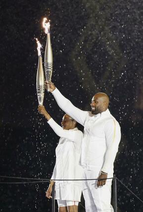 パリ五輪の開会式で、聖火を掲げる最終走者のテディ・リネール（右）とマリージョゼ・ペレクさん＝７月２６日、パリ（共同）